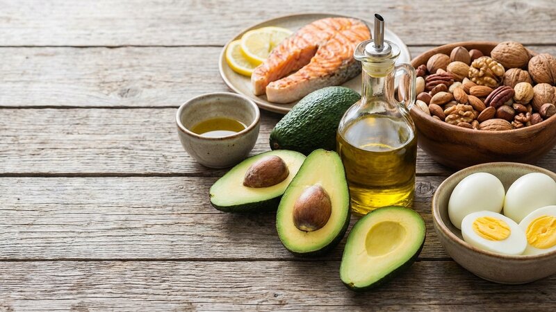 Healthy fat sources including avocados, olive oil, salmon, nuts and eggs
