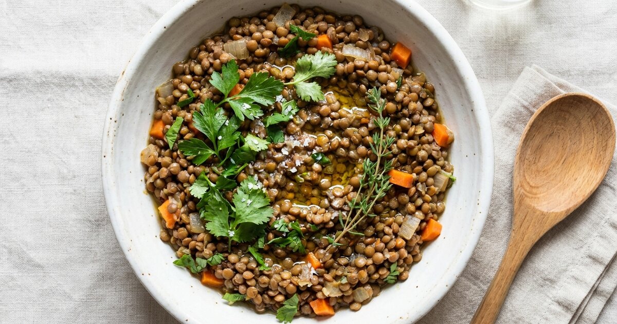 Bowl of cooked brown lentils with herbs - 18g protein, 40g carbs, 16g fiber per cup
